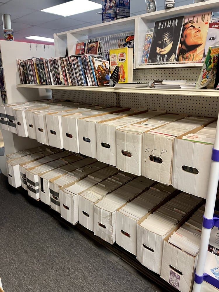 Rows of comic book boxes with Batman and Shazam comics on display